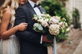 Elegant couple of blondie bride and stylish groom embracing and holding flowers. Royalty Free Stock Photo