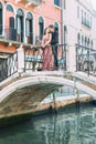 Elegant couple stands on the bridge and enjoys the view to a canal in Venice, Italy