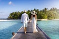 A elegant couple walks down a wooden pier over turquoise sea in the Maldives Royalty Free Stock Photo
