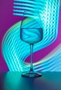 Elegant crystal glass filled with pure water on a purple background painted with blue light. Light reflections and refractions, Royalty Free Stock Photo