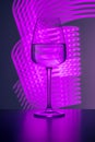 Elegant crystal glass filled with pure water on a purple background painted with colorful light. Light reflections and refractions Royalty Free Stock Photo
