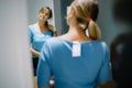 Elegant customer trying on new t-shirt in dressing room. Woman touching hair, tilting head and admiring reflection. Royalty Free Stock Photo