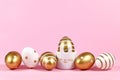 Elegant golden and white painted easter eggs with dots and stripes and cute easter egg cup in shape of bunny on pink background Royalty Free Stock Photo