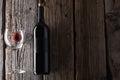 Elegant dark bottle and glass with remains of red wine on rustic wooden background. Advertising and promotion concept. Mock up. Royalty Free Stock Photo
