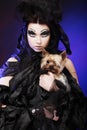 Elegant dark queen with little dog over dark background Royalty Free Stock Photo