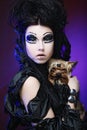 Elegant dark queen with little dog over dark background Royalty Free Stock Photo