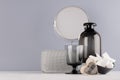 Elegant decor dressing table in minimalist style - black vase, glass, cosmetic accessories, mirror, wooden heart on grey wall.