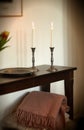 Elegant and decorative lit candles on a wooden table at home. Woven throw and house decorations for aroma, good scent