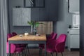 Elegant dining room interior composition with velvet chairs, design wooden table, lamps and beautiful personal accessories. Open