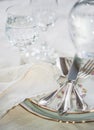 Elegant dinner set with silver knife, fork and spoon lying across luxyry porcelain dishes, and crystal glassware on cream vintage Royalty Free Stock Photo