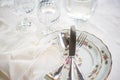 Elegant dinner set with silver knife, fork and spoon lying across luxyry porcelain dishes, and crystal glassware on cream vintage Royalty Free Stock Photo