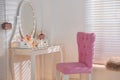 Elegant dressing table with lights and pink chair in room interior