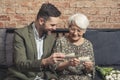 elegant elderly pensioner lady bonding with her adult grandchild by looking at old photos and talking about her life Royalty Free Stock Photo