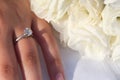 An elegant engagement diamond ring on a woman`s hand and a bouquet of white Lisianthus flowers Royalty Free Stock Photo