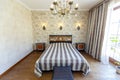 Elegant expensive bedroom with a large white bed with a striped bedspread. A high headboard with a red pattern