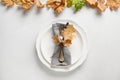 Elegant fall table setting with dry leaves and white plate on white table Royalty Free Stock Photo