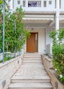 An elegant family house entrance marble covered pathway and a brown wooden door. Royalty Free Stock Photo