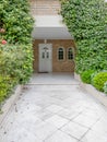 An elegant family house with stone covered walls and marble pathway between the garden to the white door. Royalty Free Stock Photo