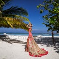 Elegant fashion model in amazing long gown dress is posing on the Maldives sandy beach. Elegance. Couture. Vogue