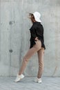 Elegant fashion model young woman in stylish glasses in black blazer in beige pants in casual shoes and fashionable straw hat near Royalty Free Stock Photo