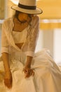 Elegant fashionable woman wearing summer white dress, straw hat, posing in stylish boho interior. Royalty Free Stock Photo