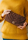 Elegant fashionable woman in yellow sweater with knitted purse. Woman holding brown knitted purse in a hands