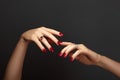 Elegant female hands with bright manicure. Square nails with red gel polish. Luxury fashion style of brilliants jewelry