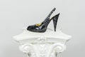 Elegant female high-heeled black snake leather shoe on greek column Royalty Free Stock Photo