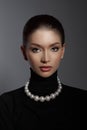 Elegant female model in a black turtleneck and lustrous pearl necklace showcases a blend of classic beauty with modern