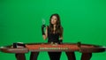 Elegant female in studio on chroma key green screen. Attractive woman in black dress at the blackjack poker table posing Royalty Free Stock Photo