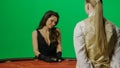 Elegant female in studio on chroma key green screen. Attractive woman in black dress and croupier at the blackjack poker Royalty Free Stock Photo