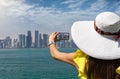 Elegant, female traveller is taking pictures of the skyline of Doha, Qatar Royalty Free Stock Photo