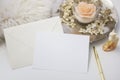 Elegant feminine stationery mockup scene with a blank paper greeting card, golden accessories, candle and flowers, on