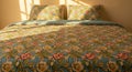 Elegant floral patterned bedspread with matching pillows in warm sunlit cozy bedroom setting Royalty Free Stock Photo