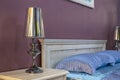 Elegant fragment of classic luxury bedroom interior with selective focus. There are a bed with satin blue linens Royalty Free Stock Photo