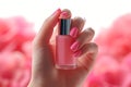 Elegant French manicure hand holds a bottle of pink polish