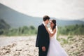 Elegant gentle stylish groom and bride near river with stones. Wedding couple in love