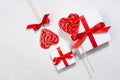 Elegant gentle wedding background - white gift boxes with red bow, sweet lollipops hearts on white wood board, top view.
