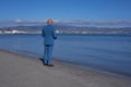 Elegant gentleman in a blue suit, strolling on Poetto Beach: a stylish contrast of formal attire against the serene coastal