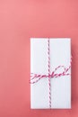 Elegant Gift Box Wrapped in White Paper Tied with Striped Twine on Cherry Pink Background. Christmas New Years Presents Shopping