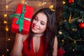 Close-up portrait of smiling girl in red dress with gift box near christmas tree Royalty Free Stock Photo