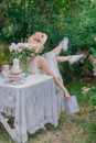 Elegant girl in straw hat with flowers and retro dress relaxing in the garden of a country house. Royalty Free Stock Photo