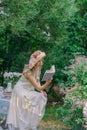 Elegant girl in straw hat with flowers and retro dress relaxing in the garden of a country house. Royalty Free Stock Photo