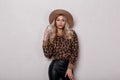 Elegant glamorous young woman with beautiful makeup with curly hair in a luxurious hat in a leopard sweater in fashionable black