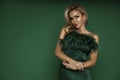 Elegant glamour blonde woman in evening feather green dress on green background in studio