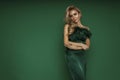 Elegant glamour blonde woman in evening feather green dress on green background in studio