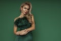 Elegant glamour blonde woman in evening feather green dress on green background in studio