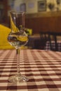 Elegant glass with alcohol on checkered red and white tablecloth. Glass of white wine. Drinks and beverages concept.