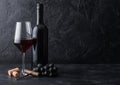 Elegant glass and bottle of red wine with corks and corkscrew on black stone background. Natural Light Royalty Free Stock Photo