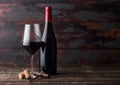 Elegant glass and bottle of red wine with corks and corkscrew on dark wooden background. Natural Light Royalty Free Stock Photo